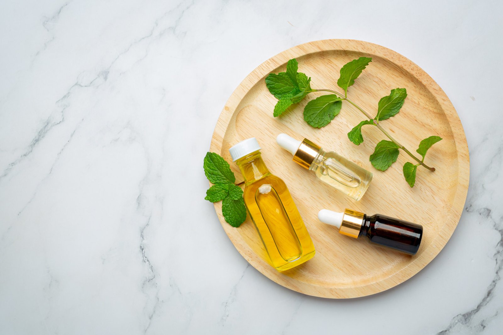 essential oil of peppermint in bottle with fresh green peppermin