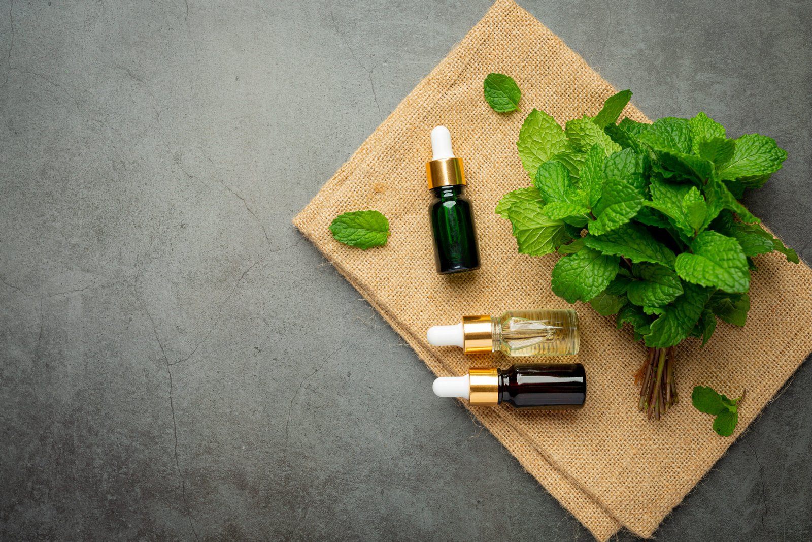 essential oil of peppermint in bottle with fresh green peppermin